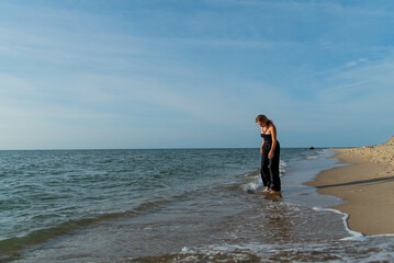 Beautiful girl wearing black dress walking on beach. See view