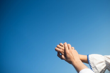 The hands of maried on the background of the sky. Sunny day . Young hands.Blue background hands up in the air. Selective focus