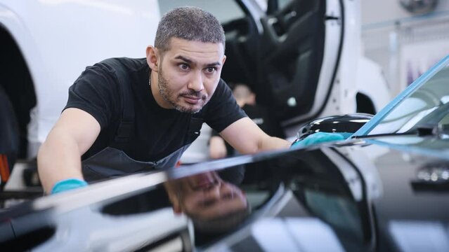 A man rubs the surface of the car after polishing. Finishing the surface, before issuing to the client.