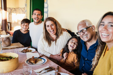 Happy latin family having fun eating together home - Focus on grandmother face - obrazy, fototapety, plakaty