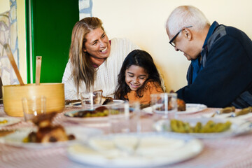 Happy grandparents eating with grand-daughter at home patio - Focus on grandmother face
