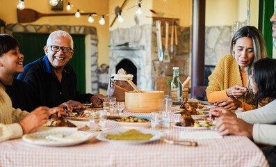 Happy latin family having fun eating together at home - Focus on grandfather face