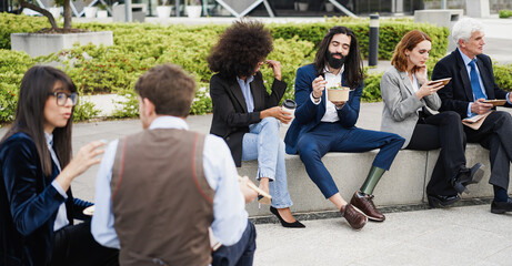 Diverse business people doing lunch break outdoor from office building - Focus on man with leg...
