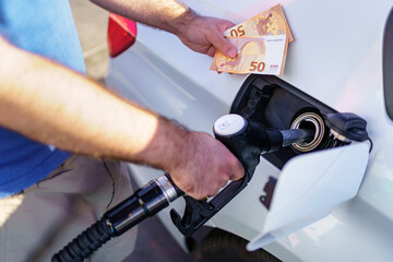 Man refueling with two fifty euro bills for the high price due to inflation.