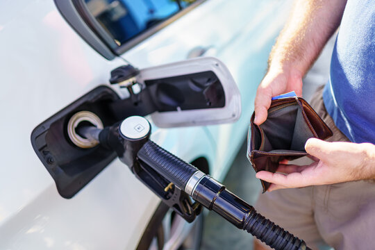 Hands of a man showing the empty wallet after refueling at a gas station.