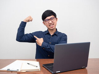 Positive man glasses sit at workspace point at his muscle about hard working