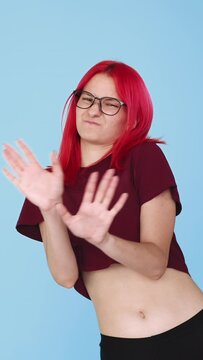 Vertical video. Refusal no. Denial gesture. Rejection protest. Disgust expression. Skeptic girl waving nope on blue background seamless loop.