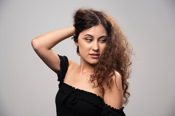 Fototapeta premium Young woman posing in black blouse with curly hair
