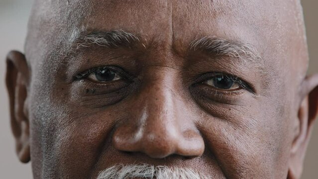 Close-up male dark eyes wrinkled face African American old man looking at camera with sad expression elderly senior man poor vision trouble eyesight problem ophthalmology insurance health care service