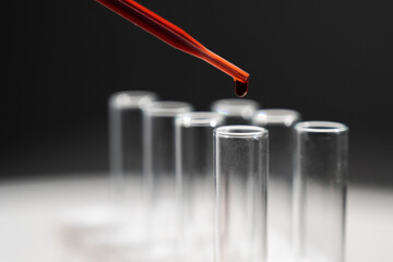 Close-up of a laboratory assistant dripping blood from a pipette into a test tube. 