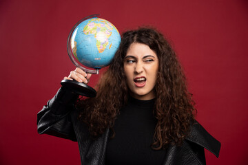 Curly woman holding globe on red background