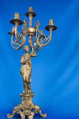 classic bronze chandelier with a figure of woman, ancient candlestick studio photo, antique candlestick isolated, brass chandelier, one vintage candlestick, bronze candle tree on blue background