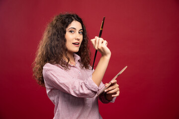Young woman holding paint brush and paint palette