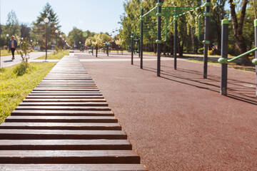 Background. A modern area for outdoor activities in the park with horizontal bars and rubber flooring. Selective focus on bench.