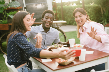 Multiethnic friends making video call during lunch