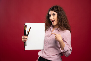 Young artist pointing at paintbrushes and canvas