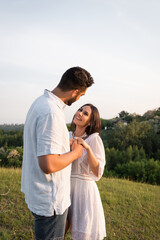 cheerful couple holding hands and looking at each other outdoors.