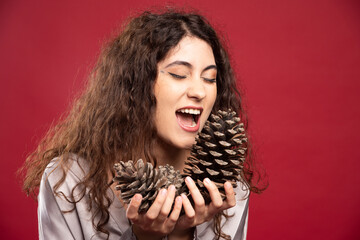 Beautiful girl looking at pinecones on red background