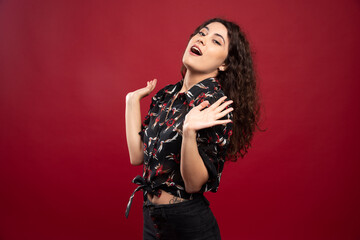 Curly woman with black blouse standing on red background