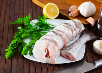 Fresh raw fillet of hake fish sliced on wooden background