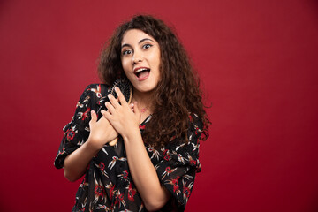 Curly woman gripping comb on red background