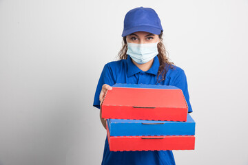 Pizza delivery girl holding three boxes with medical facemask on white background