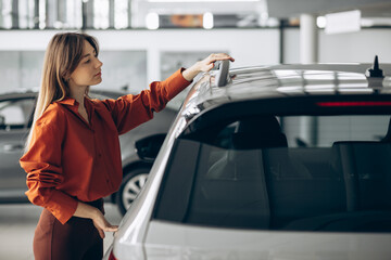 Naklejka premium Woman choosing a car in a car showroom