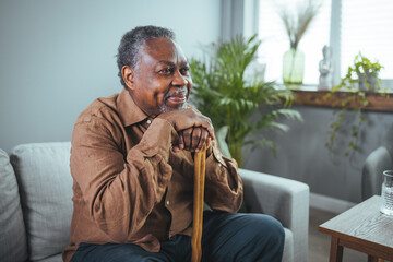 Portrait of happy senior man sitting at home with walking stock and smiling. Portrait of happy...