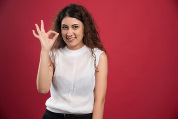 Woman with ok gesture on red background