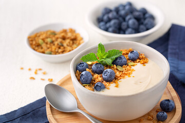 Plant organic based yogurt made from almond milk topped with granola and fresh blueberries