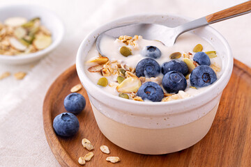 Plant based organic yogurt made from almond milk topped with gluten free granola and fresh blueberries - obrazy, fototapety, plakaty