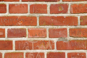 Carved writing on a solid red brick wall of a house or home. Closeup of rough texture and detail background with copyspace on brickwork. Modern architecture and masonry on the boundary of a building