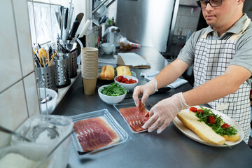 Caucasian man with down syndrome preparing a sandwich in commercial kitchen