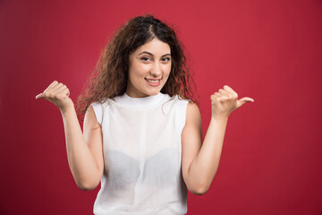 Smiling woman showing thumbs up on red background