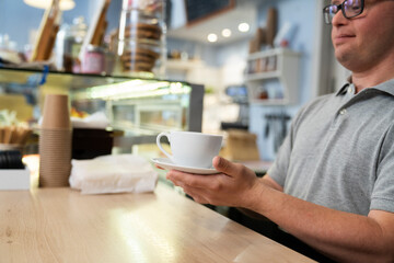 Caucasian man with down syndrome serving a cup of coffee