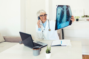 Doctor talks with patient about results while holding an x-ray in hands. A physician discusses the results with a patient or colleague via smartphone. Medicine, radiology and healthcare concept.