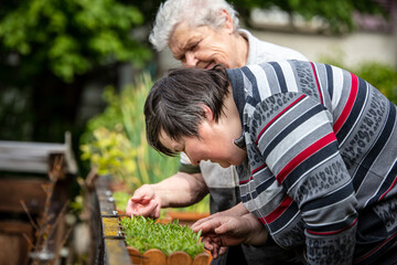 senior mother and her mentally handicapped daughter are looking at flowers