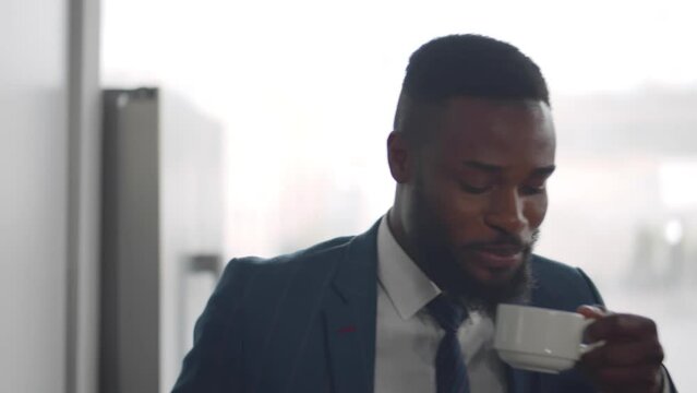 African-American businessman take coffee from coffee machine in office. Realtime