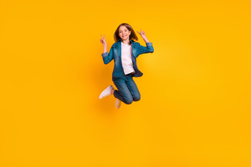 Fototapeta na wymiar Full body portrait of carefree excited girl jumping arms fingers demonstrate v-sign isolated on yellow color background