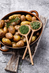 Pan filled with roasted potatoes shot on rustic wooden table.