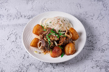kuyrdak, roast, fried potatoes with meat. on a light concrete background