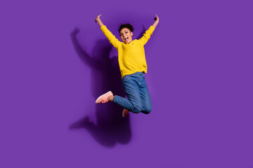 Full length photo of satisfied carefree person jumping raise fists freedom isolated on violet color...