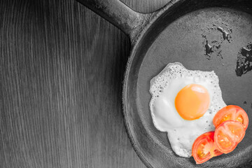 Egg, sunny side up, with fresh tomatoes in a frying pan