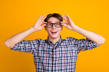 Portrait of young handsome man in shirt isolated on shine vivid background touching his glasses