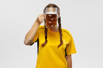 One young excited woman in yellow football kit holding beer mug and supports favorite team. Soccer fans, competition, sport, oktoberfest concept
