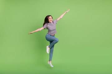 Full length photo of overjoyed glad person raise arms enjoy free time isolated on green color background
