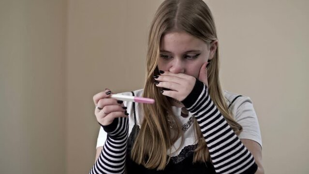 Teenage girl looks fearfully at a pregnancy test.