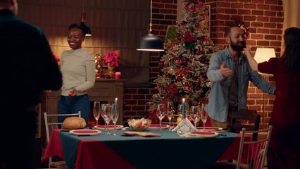 Joyful interracial couple welcoming guests to Christmas dinner at home. Festive people gathering in dining room to celebrate winter holiday with traditional home cooked food. - Powered by Adobe