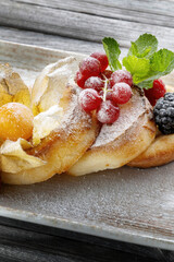 Cottage pancakes with berry jam, sour cream and berries. Sprinkled with powdered sugar. vertical photo