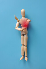 A wooden figure of a man holding his elbow. Elbow pain. Elbow injury